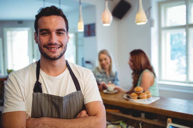 Portrait de barista heureux avec les bras croisés au café