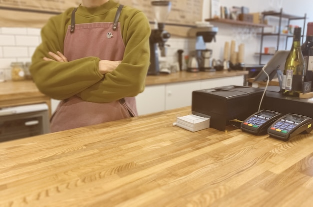 Portrait d'un beau barista en pull vert et tablier au bar du café moderne