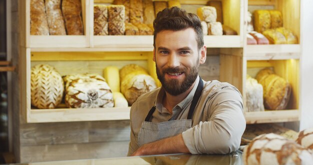 Portrait de beau boulanger souriant travaillant dans une boulangerie