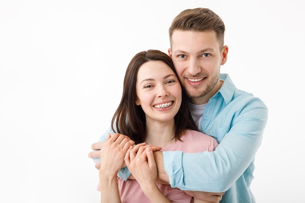 Portrait d'un beau couple bien-aimé Un gars et une fille s'embrassent et regardent la caméra en souriant Sur un fond blanc