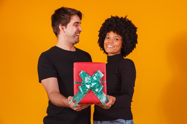 Portrait d'un beau couple sur jaune avec un cadeau