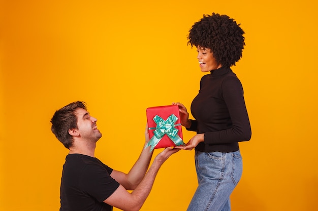 Portrait d'un beau couple sur jaune avec un cadeau