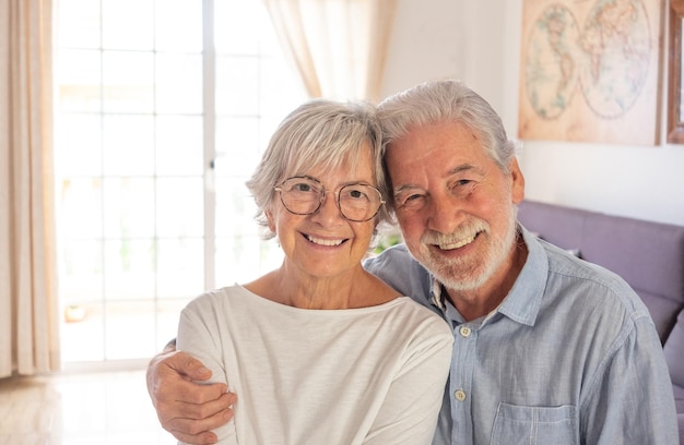 Portrait d'un beau couple de personnes âgées assis à la maison souriant regardant la caméra