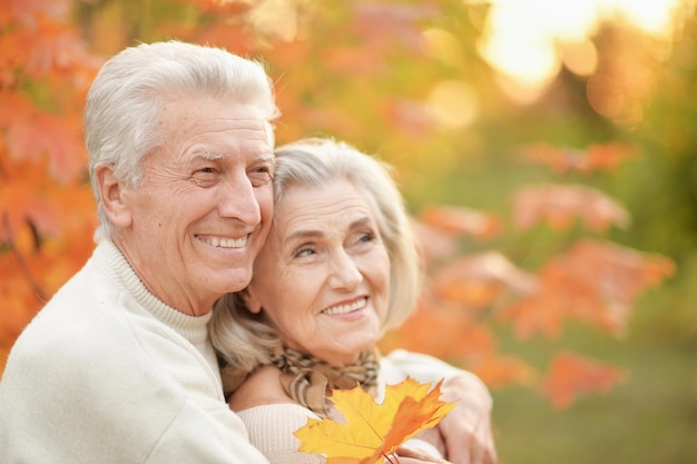 Portrait d'un beau couple de personnes âgées heureux avec des feuilles d'automne