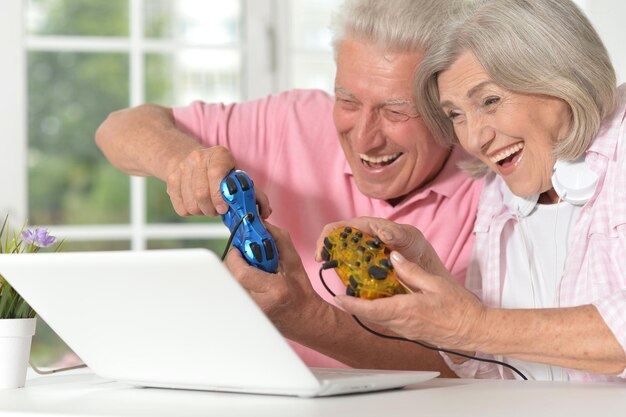 Photo portrait d'un beau couple de personnes âgées heureux jouant à un jeu d'ordinateur