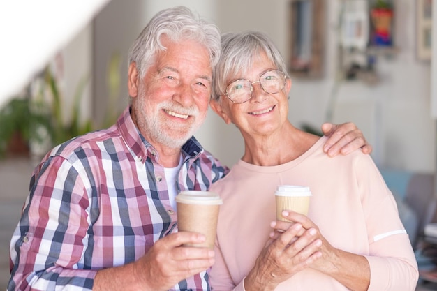 Portrait d'un beau couple de personnes âgées regardant la caméra tenant une tasse de café Joyeux et souriant beau couple de personnes âgées à l'intérieur étant de bonne humeur