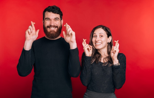 Portrait de beau couple rêvant avec les doigts croisés