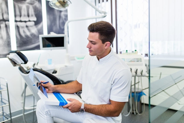 Portrait d'un beau dentiste souriant regardant l'image radiographique de son patient.