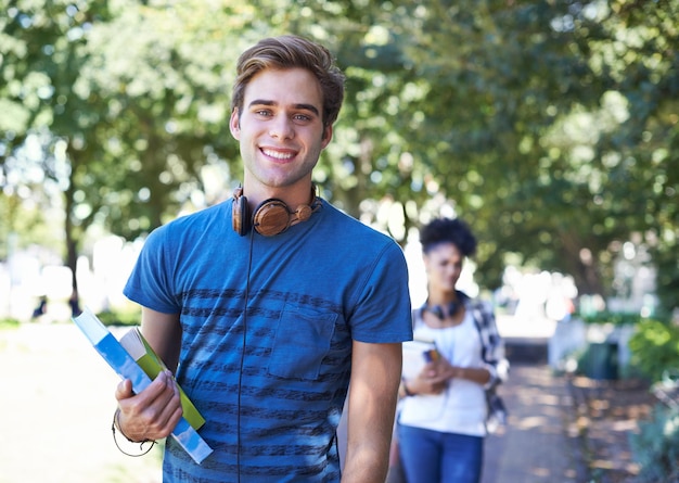 Portrait d'un beau étudiant marchant au collège avec ses livres à la main