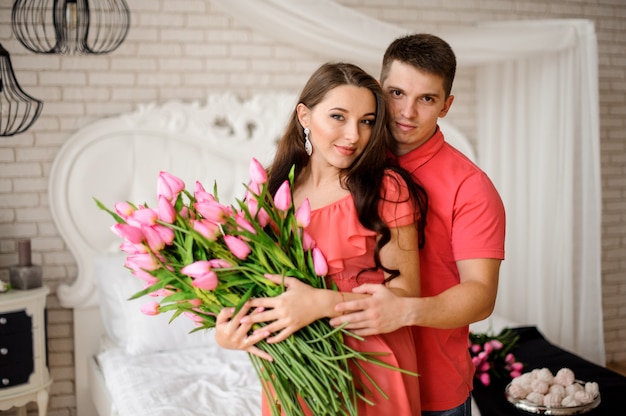 Portrait de beau et jeune couple avec gros bouquet de tulipes roses