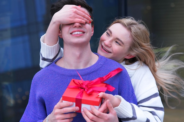 Portrait d'un beau jeune couple heureux, d'une adolescente et d'un adolescent. Un beau mec petit ami étreint sa petite amie et lui donne une boîte avec un cadeau à la Saint-Valentin. Amour, bonheur