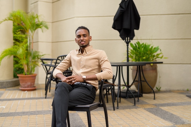 Portrait de beau jeune homme d'affaires africain noir portant des vêtements décontractés à l'extérieur dans la ville