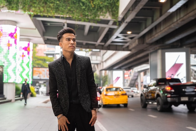 Portrait de beau jeune homme d'affaires en attente de taxi