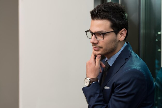 Portrait de beau jeune homme d'affaires confiant debout bras croisés