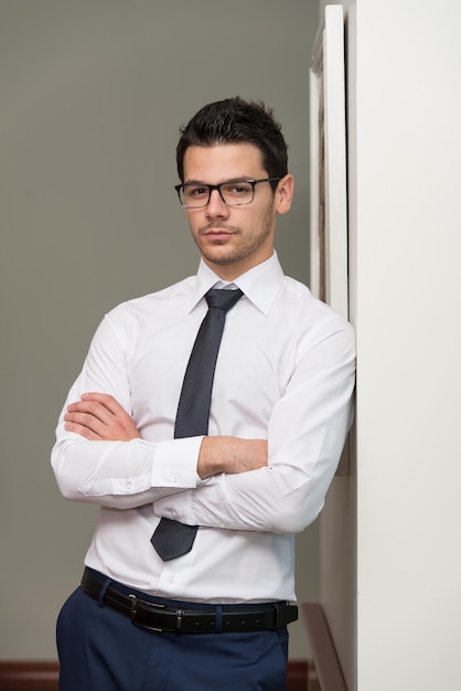 Portrait de beau jeune homme d'affaires confiant debout bras croisés