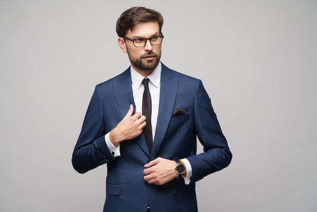 Portrait d'un beau jeune homme d'affaires élégant portant des lunettes sur le mur gris
