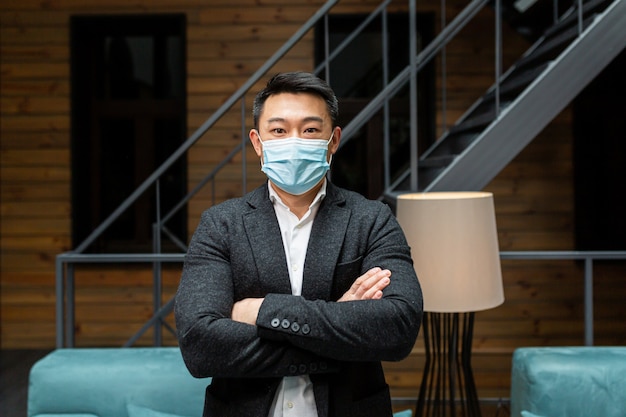 Portrait d'un beau jeune homme d'affaires professionnel asiatique chinois en costume portant un masque médical protecteur sur son visage