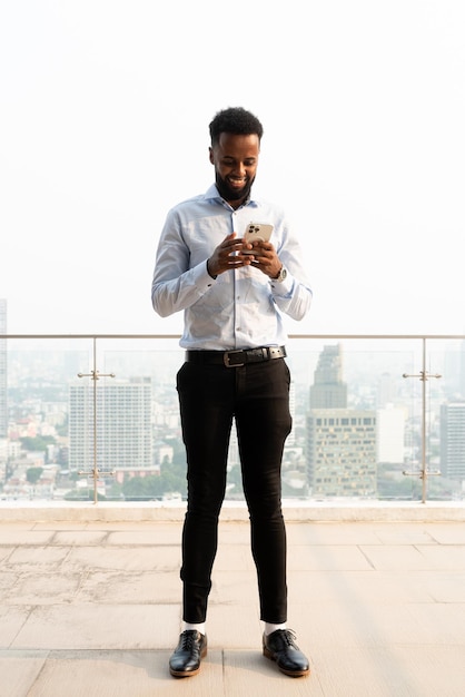 Portrait d'un beau jeune homme africain utilisant un téléphone portable