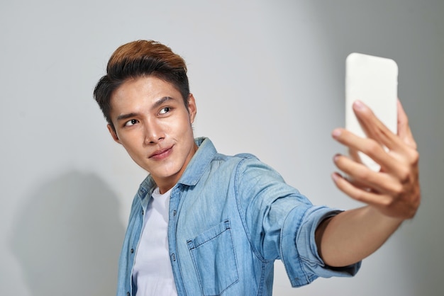 Portrait d'un beau jeune homme asiatique faisant une photo de selfie