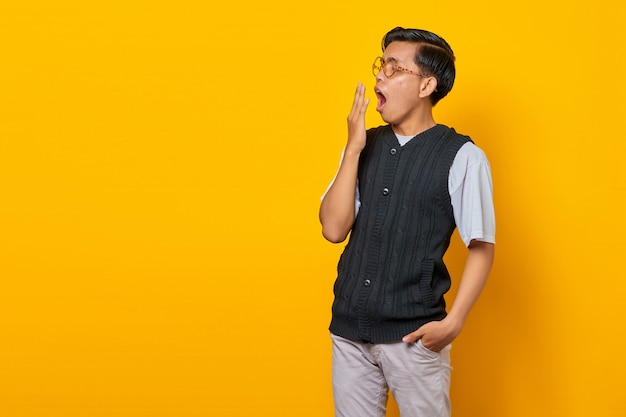 Portrait de beau jeune homme asiatique se sentant somnolent et couvrant la bouche avec la main