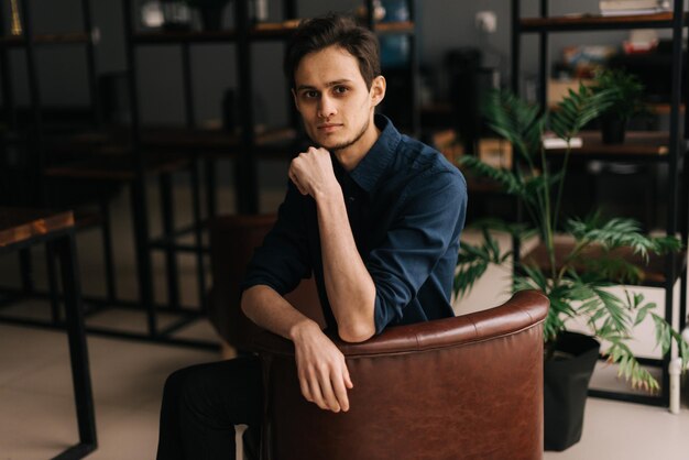 Portrait d'un beau jeune homme assis au bureau sur le lieu de travail en regardant la caméra