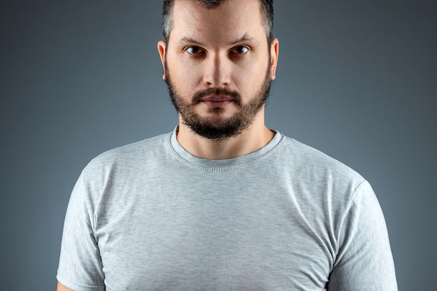 portrait Beau jeune homme barbu sur une surface grise.