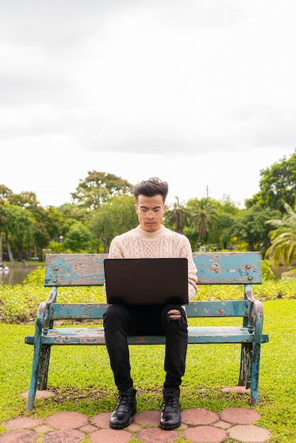 Portrait De Beau Jeune Homme Dans Le Parc Pendant L'été à L'aide D'un Ordinateur Portable