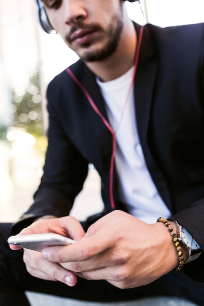 Portrait de beau jeune homme écoutant de la musique avec un téléphone portable dans la rue.