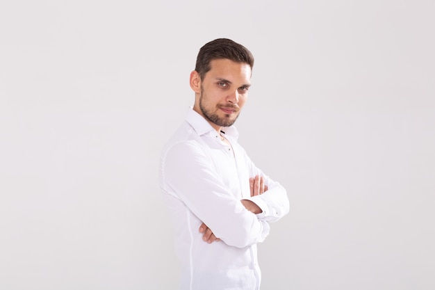 Portrait de beau jeune homme heureux en chemise décontractée debout contre un mur blanc avec