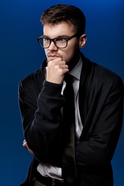 Portrait d'un beau jeune homme avec des lunettes et une chemise blanche sur fond bleu