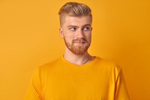 Portrait de beau jeune homme de race blanche avec barbe sur fond jaune regardant à droite