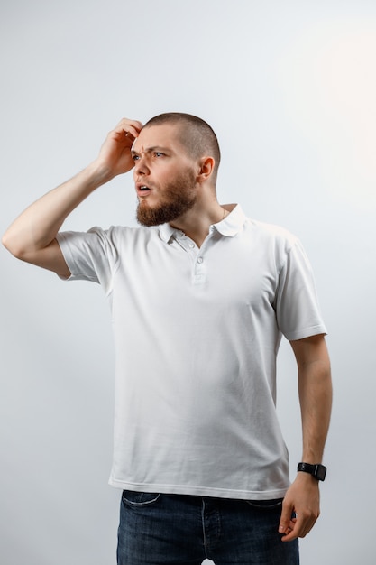 Portrait d'un beau jeune homme regardant attentivement sur le côté sur un fond blanc