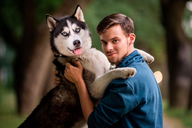 Portrait d'un beau jeune homme et de son chien Husky sibérien dans la nature