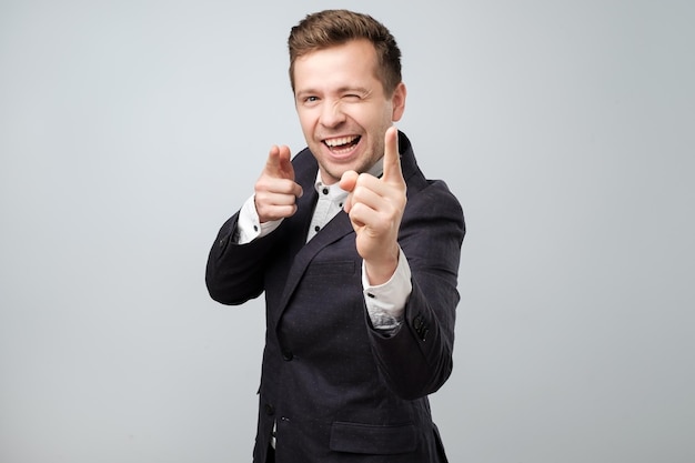 Portrait d'un beau jeune homme souriant pointant du doigt la caméra en vous choisissant comme gagnant