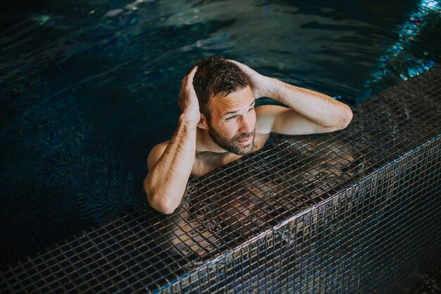 Portrait d'un beau jeune homme souriant se relaxant au bord de la piscine