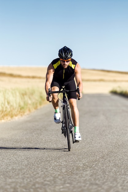 Portrait de beau jeune homme à vélo sur la route.