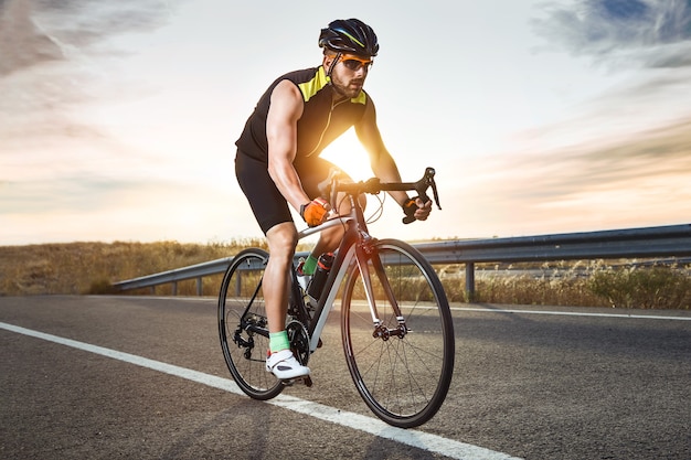 Photo portrait de beau jeune homme à vélo sur la route.