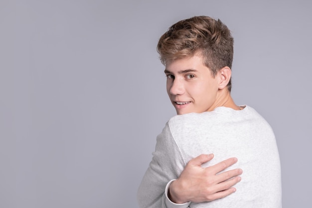 Portrait d'un beau mec adolescent se serrant dans ses bras