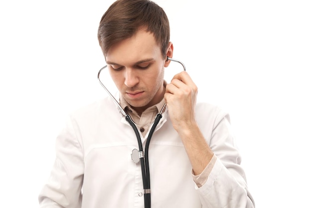 Portrait de beau médecin en blouse médicale blanche avec stéthoscope sur fond blanc avec espace de copie