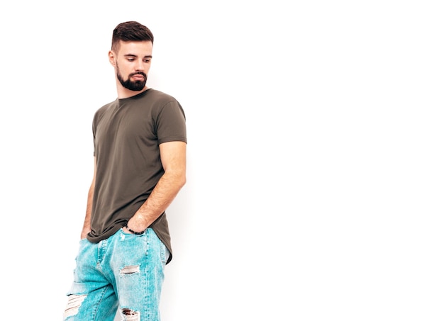 Portrait de beau modèle confiant hipster élégant hipster lambersexuel vêtu d'un t-shirt et d'un jean Mode homme isolé sur mur blanc en studio