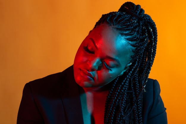 Portrait de beau modèle féminin afro-américain posant. Lumière colorée.