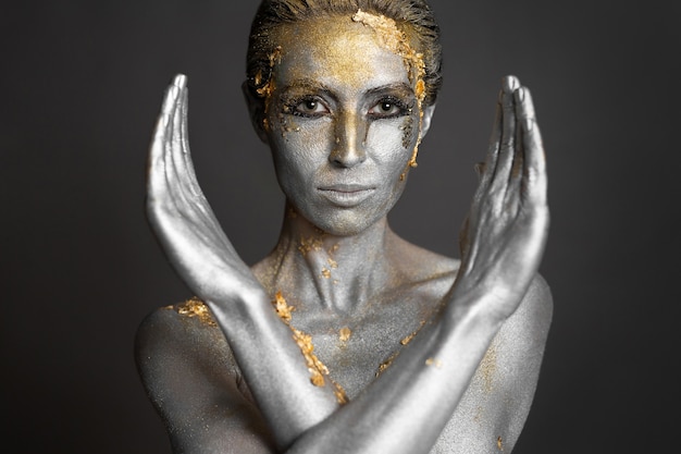 Portrait d'un beau modèle féminin avec de la peinture or et argent sur sa peau et ses cheveux en studio.