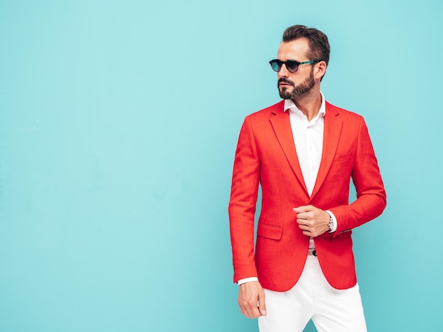 Portrait d'un beau modèle hipster élégant et confiant modèle sexuel Sexy homme moderne vêtu d'un élégant costume rouge