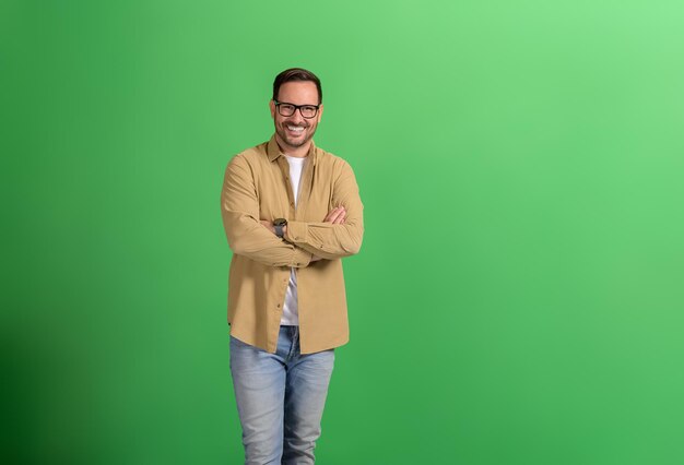 Photo portrait d'un beau professionnel avec les bras croisés et des lunettes sur fond vert