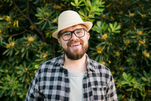 Portrait beau rire homme sur buisson vert en dehors de l'été et concept émotionnel