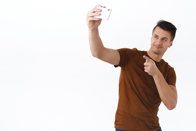Portrait d'un beau sportif caucasien impertinent entraîneur de gym athlétique diffusant en direct ou bloguant sur un mode de vie sain et une séance d'entraînement sur l'auto-quarantaine de verrouillage prenant un selfie sur un téléphone mobile