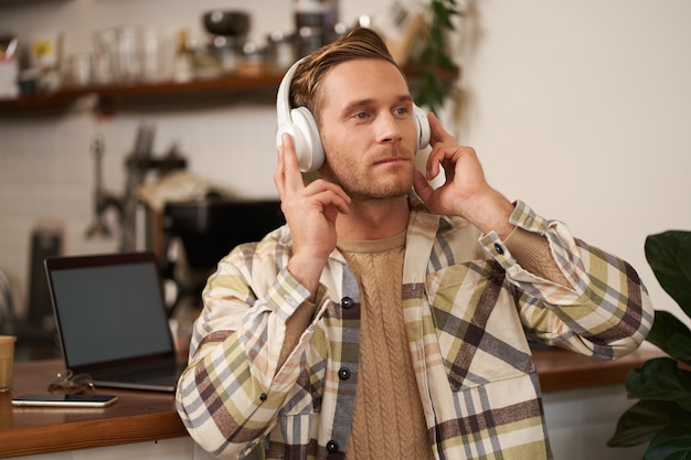 Portrait d'un beau type heureux indépendant travaillant et écoutant de la musique dans des écouteurs sans fil