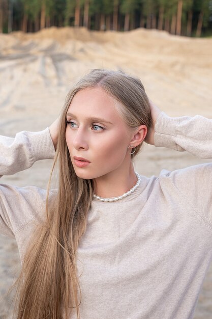 Portrait de beauté à l'extérieur sur le sable en face de la forêt, jolie pose féminine.