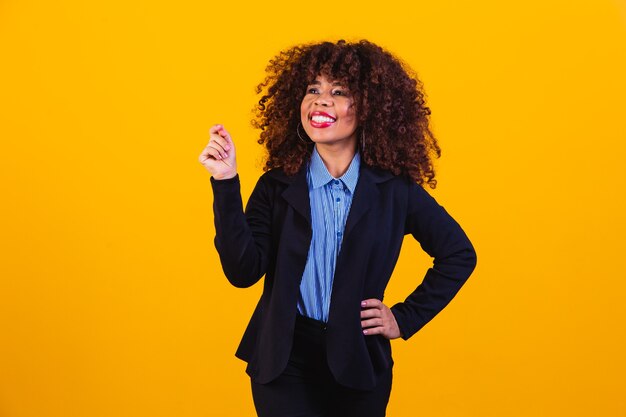 Portrait de beauté d'une femme afro-américaine avec une coiffure afro et un maquillage glamour. femme brésilienne. Race mixte. Cheveux bouclés. Coiffure. Fond jaune. Femme afro souriante à la caméra