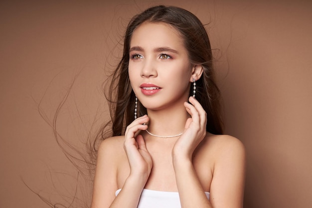 Portrait de beauté d'une femme avec des bijoux, des boucles d'oreilles dans les oreilles et un collier autour du cou. Peau du visage parfaitement propre, cosmétiques naturels